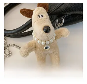 Détail du charm de sac chien en peluche avec collier de perles et pendentif cœur sur sac noir