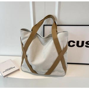 Detail view of the canvas tote bag showing crossed contrast straps and durable texture