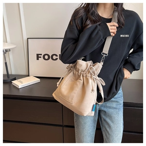 Détail du sac fourre-tout en toile beige avec fermeture à cordon et bandoulière grise
