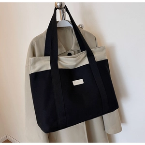 Detail of canvas tote bag showing black shoulder straps and SHUNUO brand label