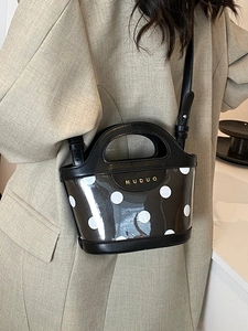 Polka dot bucket bag with gold hardware and adjustable strap shown on shoulder