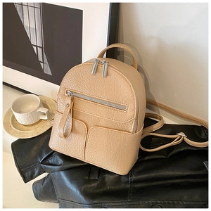 Detail view of khaki mini backpack featuring pebbled faux leather and silver metal zippers