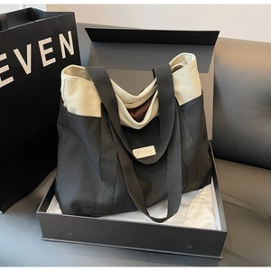 Detail of contrast canvas tote bag with leather logo patch in an elegant gift setting