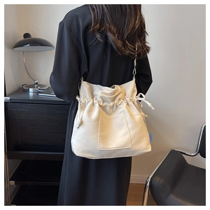 Détail du sac en toile plissé crème avec cordon de serrage et étiquette bleue