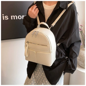 Close-up of pebble-textured cream leather mini backpack with silver metal zippers