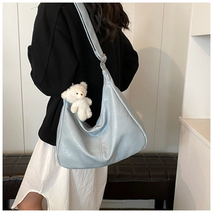Détail d'un sac bandoulière en similicuir bleu clair avec un joli charme d'ourson