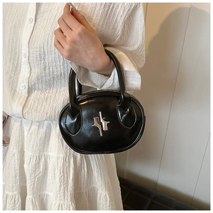 Close-up of black glossy leather handbag featuring silver abstract metal buckle and sleek design
