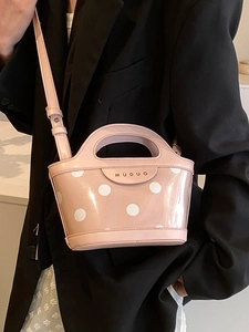 Pink polka dot crossbody bucket bag with metallic logo and adjustable strap for women