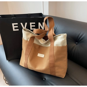Detail of contrast stitching and leather brand tag on large canvas tote bag