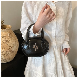 Macro shot of stylish black crossbody bag with silver logo on white pleated fabric