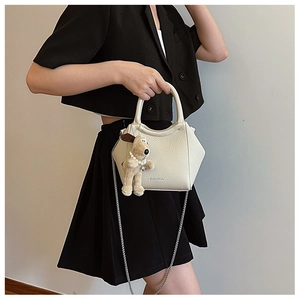 Détail d'un sac seau hexagonal beige en cuir grainé avec breloque chien peluche