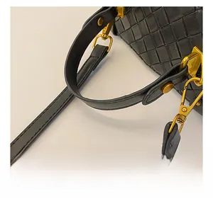 Detail of black woven leather bucket bag featuring round handle and gold hardware