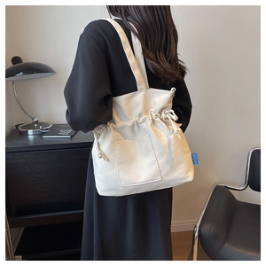 Détail du sac fourre-tout plissé blanc cassé avec cordon latéral et étiquette bleue