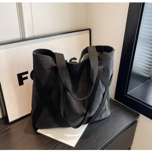 Close-up of black canvas tote bag with textured crisscross woven straps and large opening