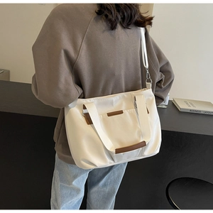 Detailed view of white canvas tote bag with brown leather trim and adjustable shoulder strap