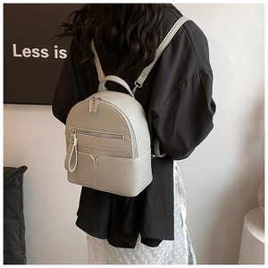 Back view of model wearing a mini light grey pebble leather backpack with slim straps