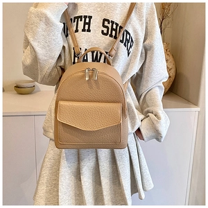 Close-up of khaki pleated leather backpack with metal zippers and magnetic flap pocket