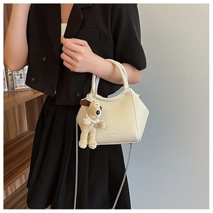 Détail du sac seau en cuir grainé blanc cassé avec pendentif chiot en peluche et chaîne