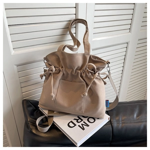Détail du sac en toile kaki avec fermeture à cordon, nœud décoratif et garnitures argentées