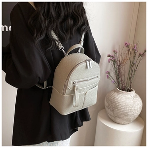 Close-up of mini light green leather backpack with lychee texture and zipper detail