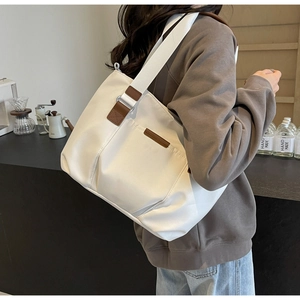 Detailed shot of large white canvas tote bag with brown leather accents and wide strap