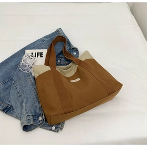 Detail of contrast color canvas tote bag resting on denim jacket with lifestyle decor