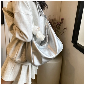Sac hobo argenté avec fermeture zippée et charm ours en peluche sur l'épaule