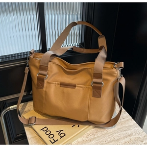 Detail of khaki nylon tote bag with adjustable strap on a textured stone table