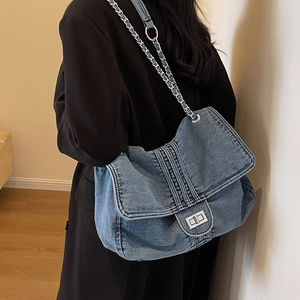 Sac fourre-tout en denim bleu délavé avec fermoir rotatif argenté et bandoulière en chaîne