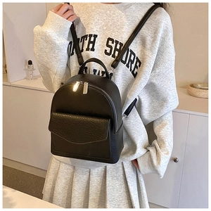 Detail view of a black pleated ballet-style backpack with silver dual zipper and litchi texture