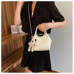 Détail du sac seau blanc cassé avec chaîne argentée et charm chien en peluche marron
