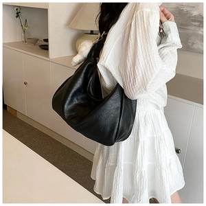 Vue détaillée du sac hobo noir en cuir texturé mat avec un pendentif en fourrure blanche