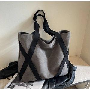 Detail of grey canvas tote with black X-shaped strap reinforcement and spacious interior