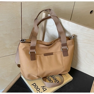 Detail of khaki nylon tote bag with large capacity, brown straps and leather edge reinforcement