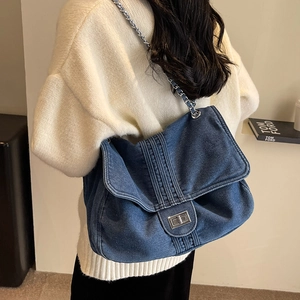 Sac cabas en denim bleu délavé avec chaîne argentée porté à l'épaule par le mannequin