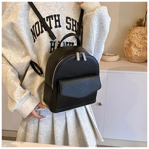 Detail of black mini backpack with lychee texture leather and silver double zippers