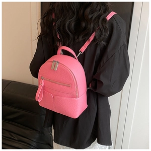 Detailed back view of a mini rose red litchi grain leather backpack on a model