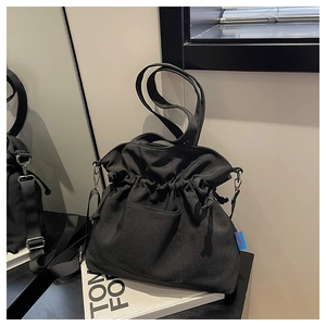 Détail du sac fourre-tout noir en toile avec étiquette latérale et large bandoulière