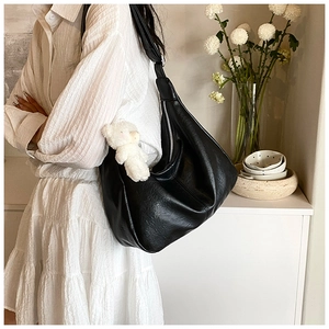 Détail du sac à bandoulière noir en cuir avec zip argenté et charm ours en peluche blanc