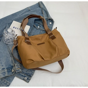 Detail view of caramel nylon tote bag with decorative leather strap on denim jacket