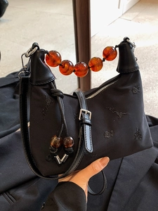 Elegant black nylon Boston bag featuring amber bead handle and floral embroidery detail