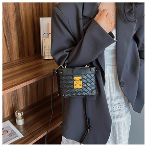Detailed shot of black quilted box bag with gold hardware worn cross-body style