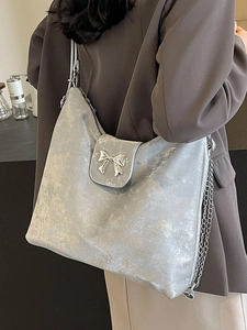 Sac fourre-tout argenté métallisé avec noeud et bandoulière chaîne porté par un modèle