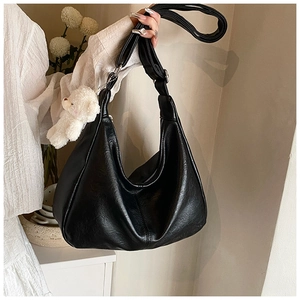 Détail d'un sac hobo noir en cuir grainé avec un adorable pendentif ours en peluche blanc