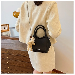 Détail du sac seau en cuir noir avec chaîne en métal et pendentif chien mignon attaché