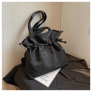 Détail du sac cabas en toile noire avec fermeture à cordon et grande poche frontale