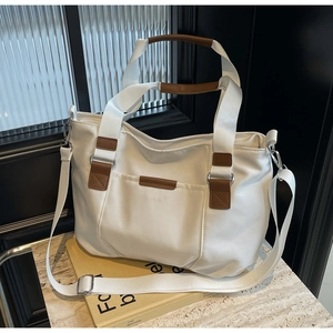 White nylon tote bag with brown leather handles and adjustable wide fabric strap detail