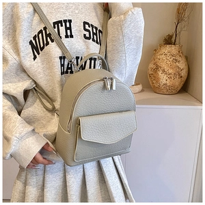 Detail of sage green pebbled leather backpack with silver zippers and front pocket