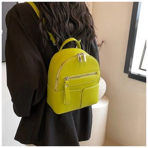 Neon lime green mini backpack in pebble leather worn by model from a side angle view