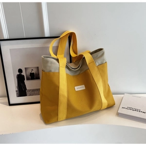 Close-up of contrast canvas tote bag with wide straps and white logo patch